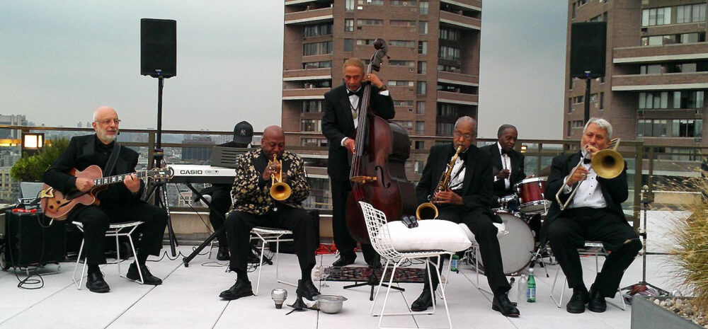 The band is pictured playing in formalwear on a Harlem rooftop.