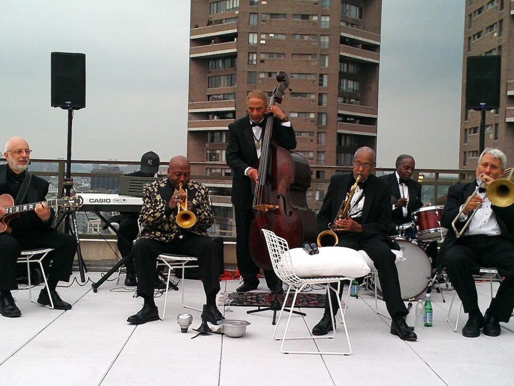 The band is pictured playing in formalwear on a Harlem rooftop.