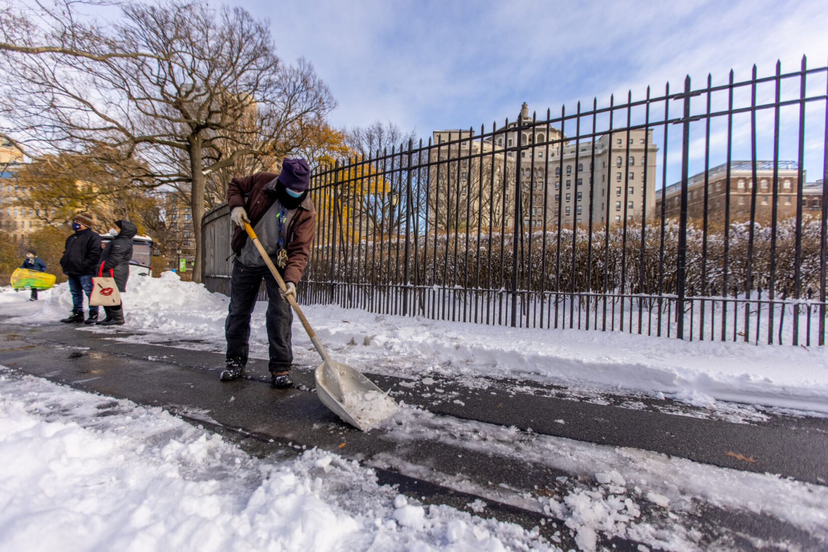 A conservancy staff member clears a path of snow on a bright winter day