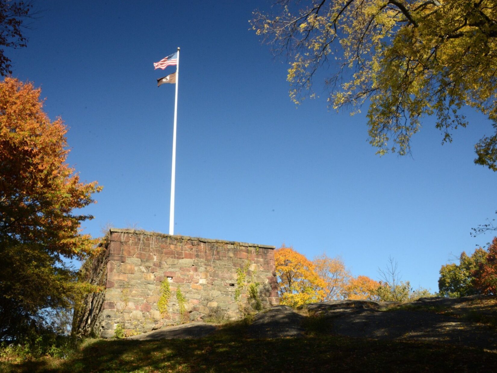 Two flags at the top of a white flagpole on the roof of the Blockhouse.