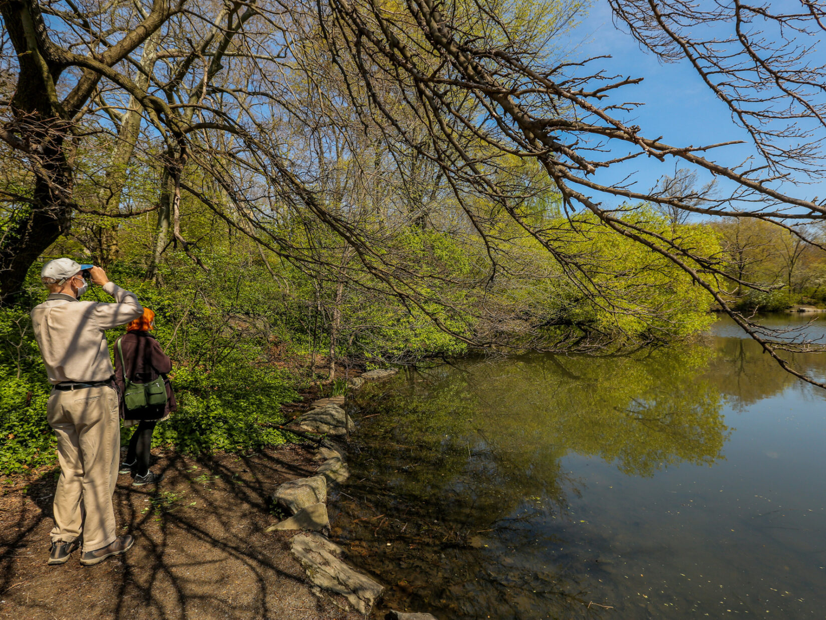 A birder using binoculars on the shore of the Lake