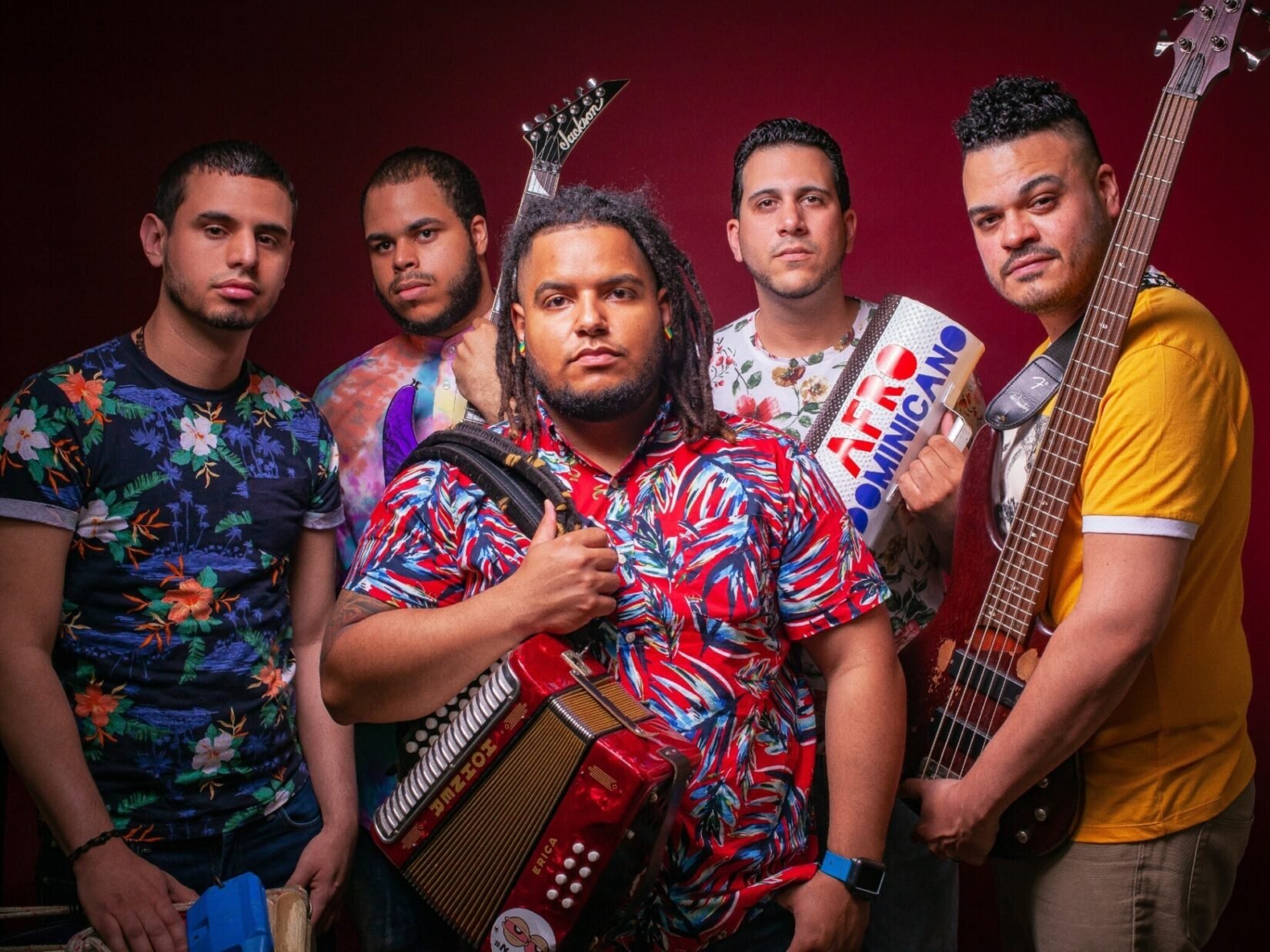 Members of the band pictured with their instruments against a red backdrop.