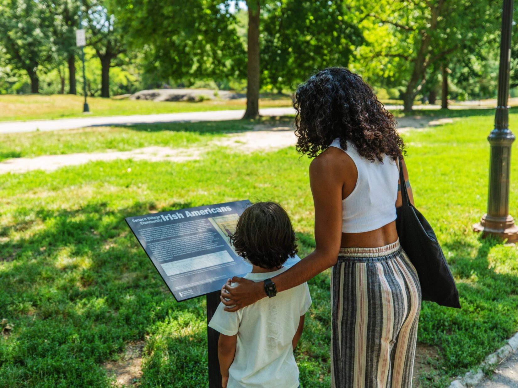 A woman and a child reading one of the in-Park signs describing Seneca Village
