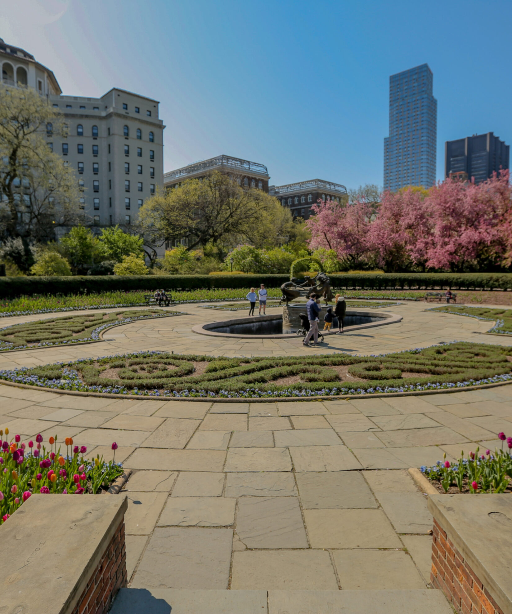A section of Conservatory Garden pictured under a cloudless blue sky, showing the early blooms of spring.
