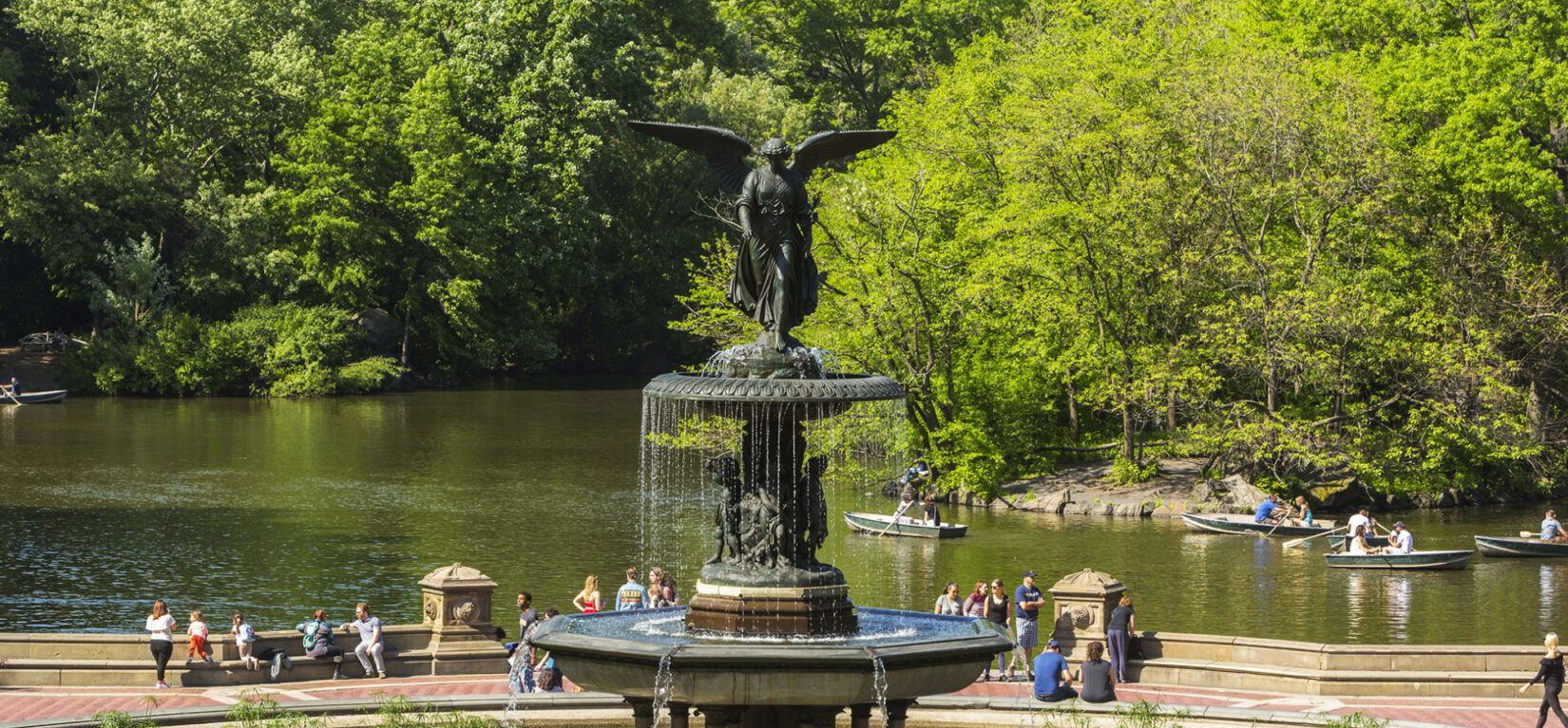 Bethesda Fountain with parkgoers behind it and boaters on the Lake behind them