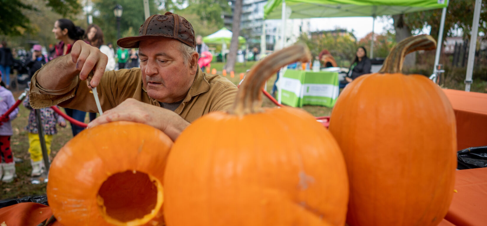 A Park staff member carving his way through a several pumpkins