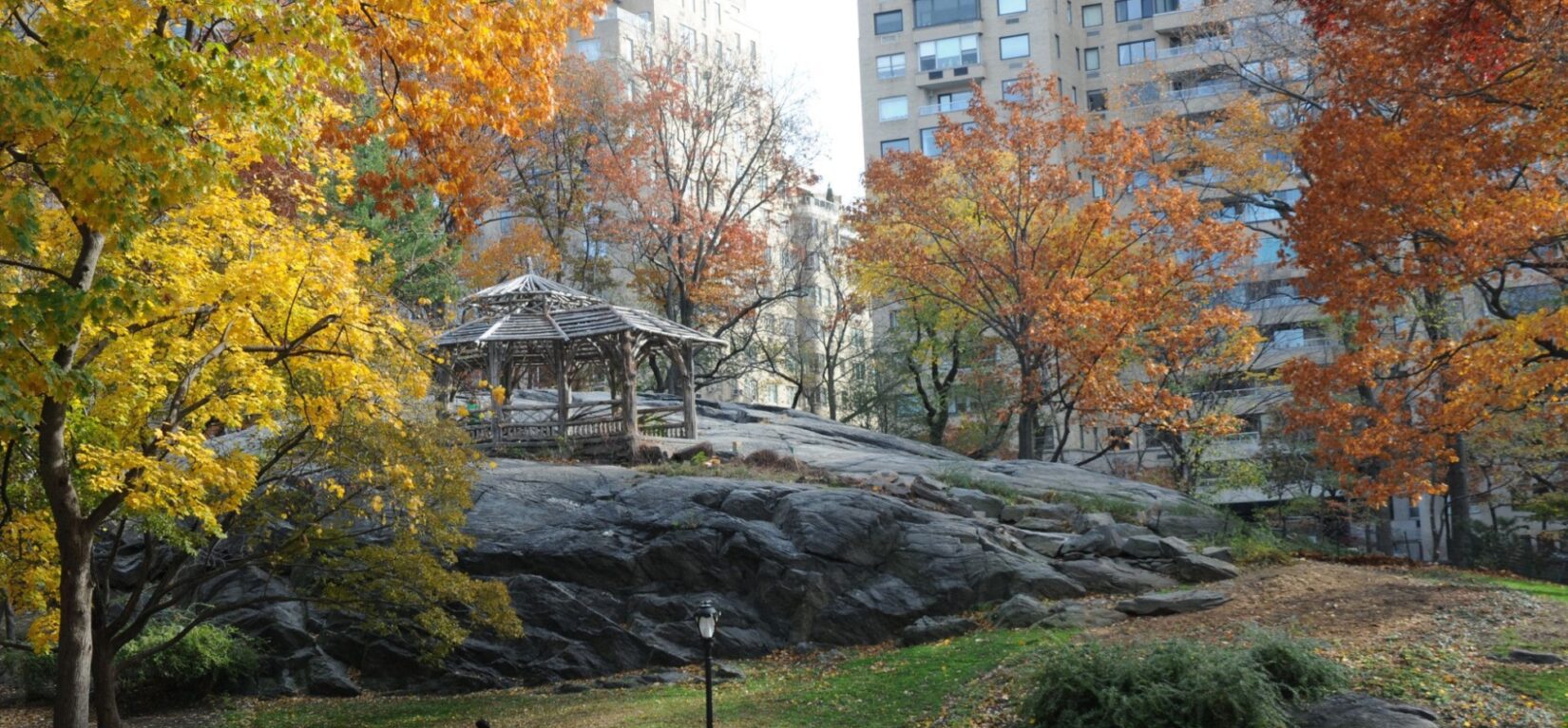 A rustic structure perches atop a large schist outcropping surrounded by fall trees
