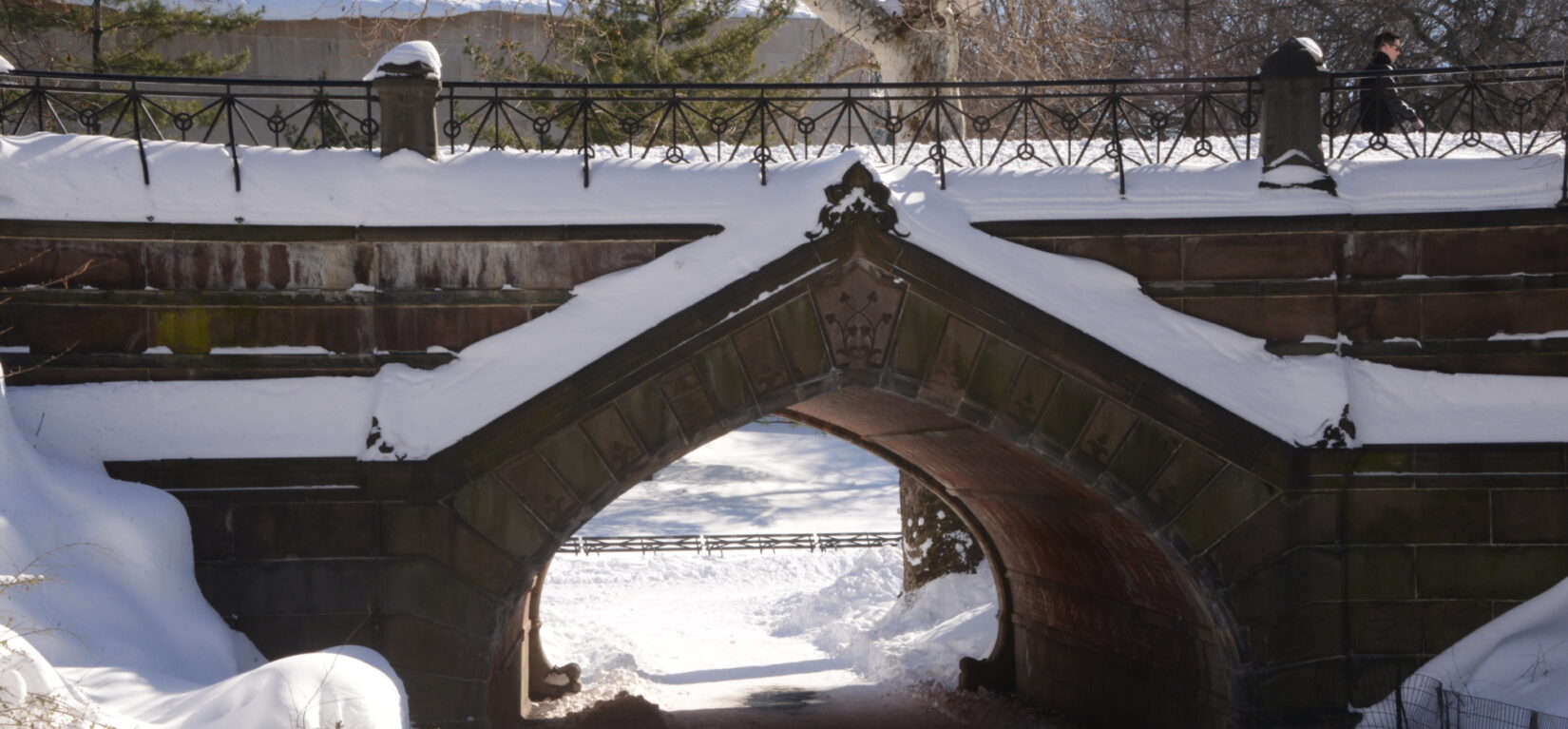 A pedestrian makes his away across the top of a snow-packed archway