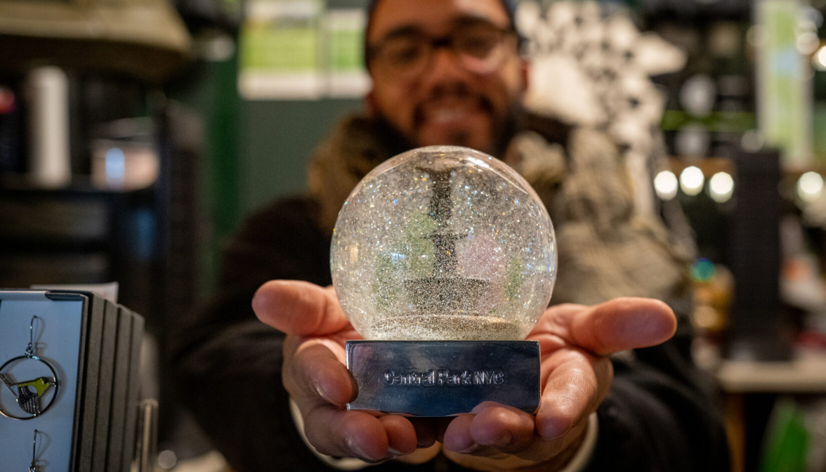 Close-up of hands holding a snow globe of Bethesda Fountain
