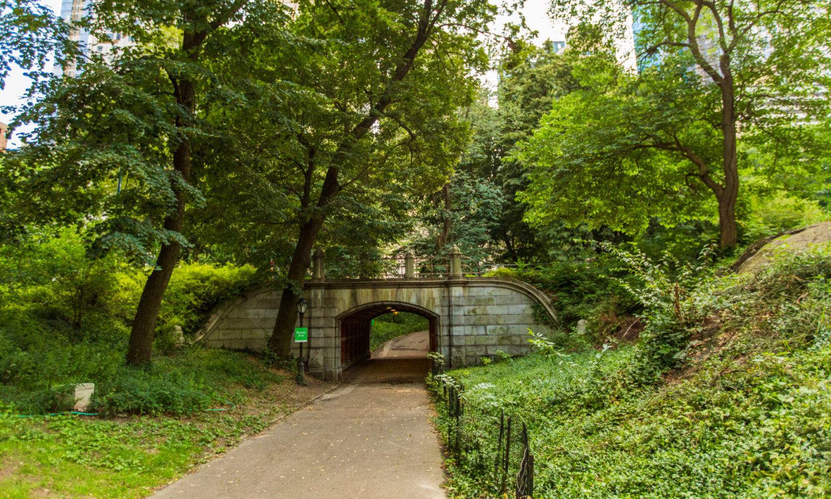 The arch straddling a Park path, nestled between banks of greenery