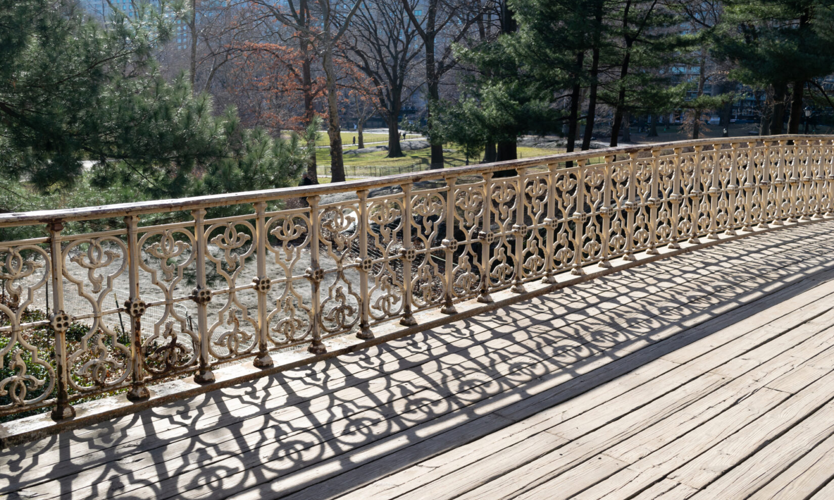 The intricate ironwork of the arch casts interesting shadows on wooden planking.