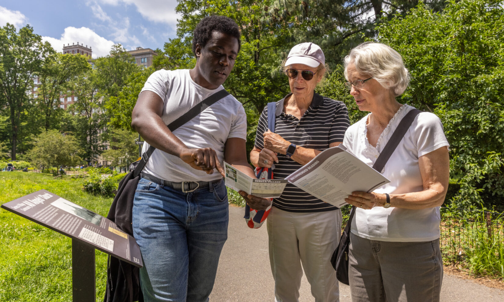 A group of people reading informational leaflets while touring Seneca Village