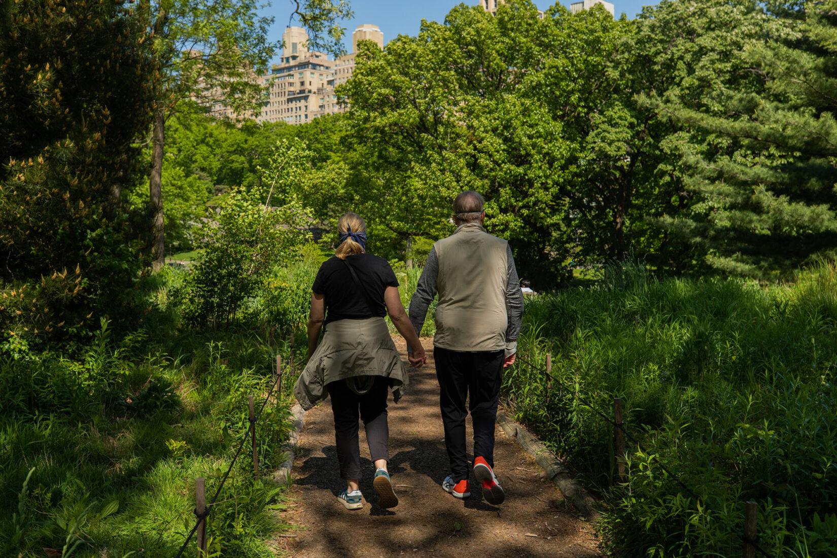 A couple walk hand-in-hand down a romantic, sunlit footpath