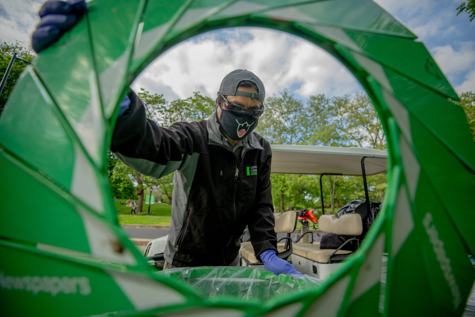 Staff member Danilo Maturan seen through the open lid of one of Central Park's signature trash bins