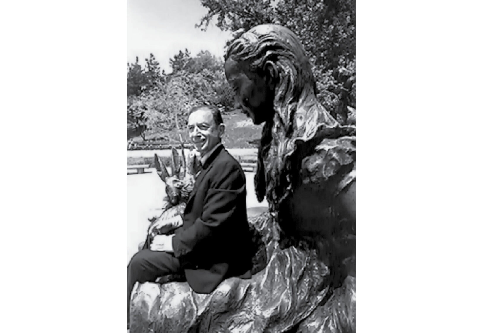 George Delacorte seated on the lap of the Alice in Wonderland statue