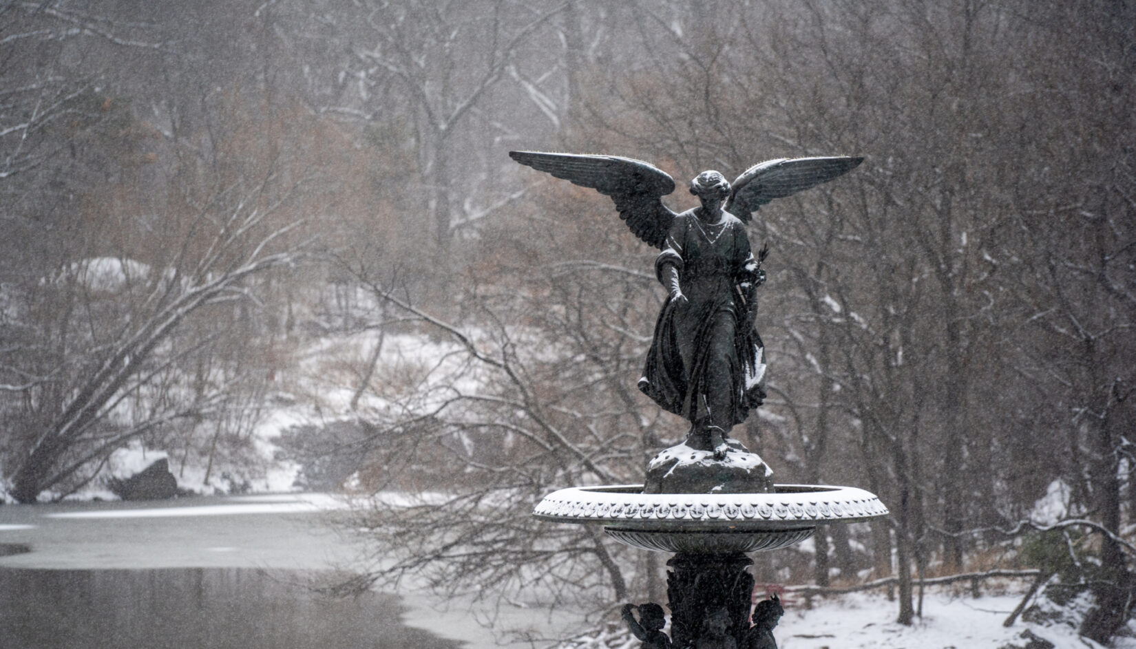 The fountain at Bethesda Terrace, dusted with snow, with the wintery Lake in the background.