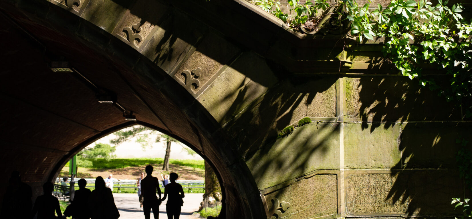 Strollers are silhouetted under the Greywacke Arch